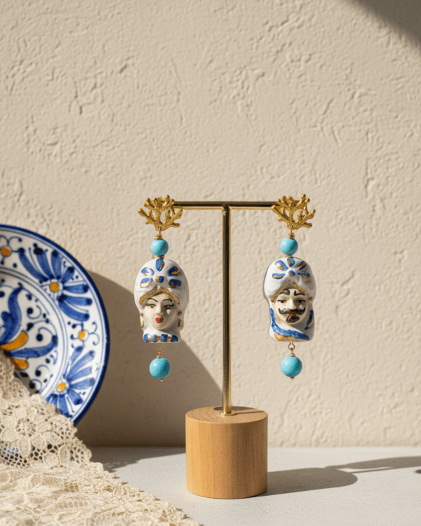 Pendientes Alessandro y Palmira Coral de Haydée en un expositor junto a un plato de cerámica siciliana