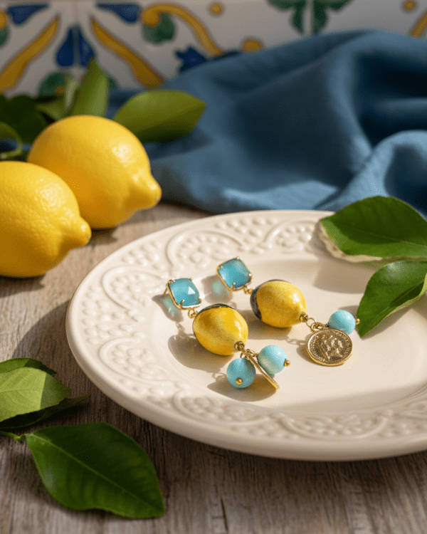 Pendientes Ricco Limón Azul de Haydée en un plato de cerámica siciliana junto a limones