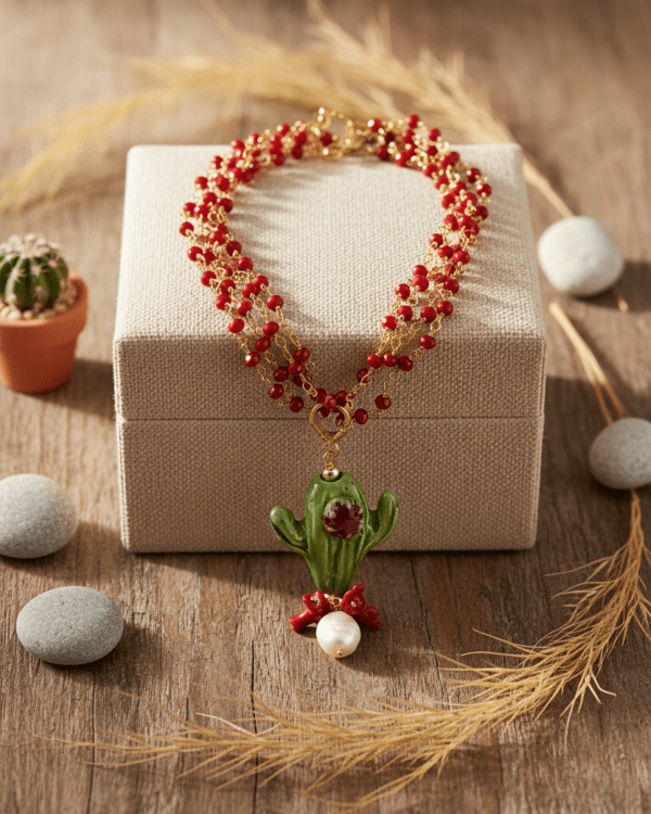 Collar Cactus de Haydée sobre una caja de regalo, con cuentas rojas y colgante de cactus de cerámica siciliana