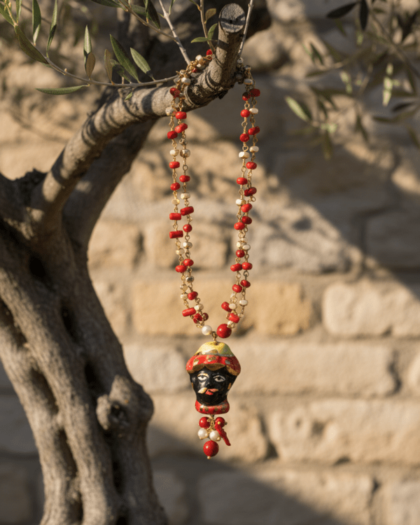 Collar Basilio de Haydée con testa di moro de cerámica siciliana, colgado de un olivo junto a un muro de piedra