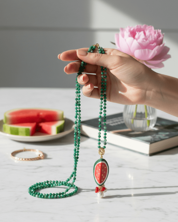 Collar Rajita de Sandía de Haydée en la mano, con cuentas verdes y colgante de sandía de cerámica siciliana