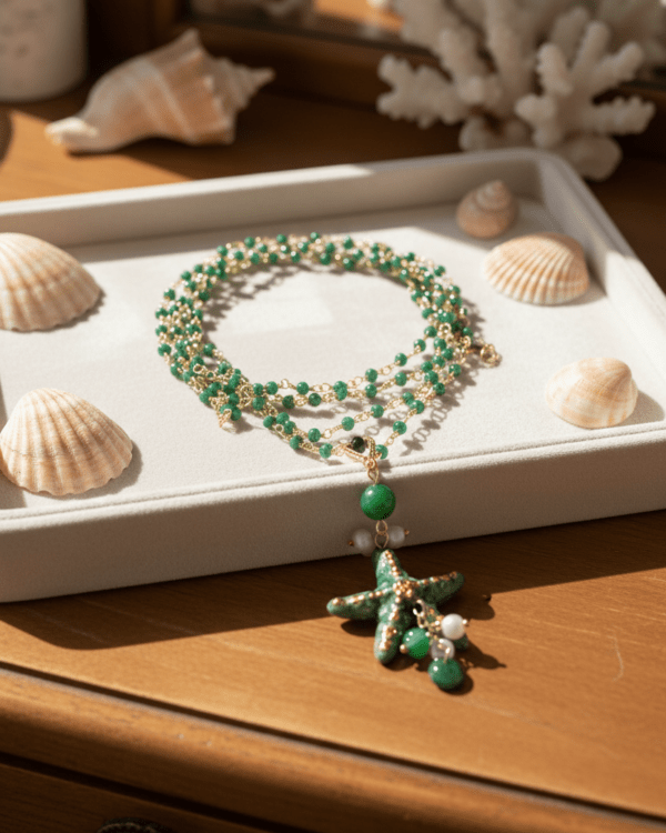 Collar Stella di Mare Verde de Haydée en una bandeja con conchas, con cuentas verdes y estrella de cerámica